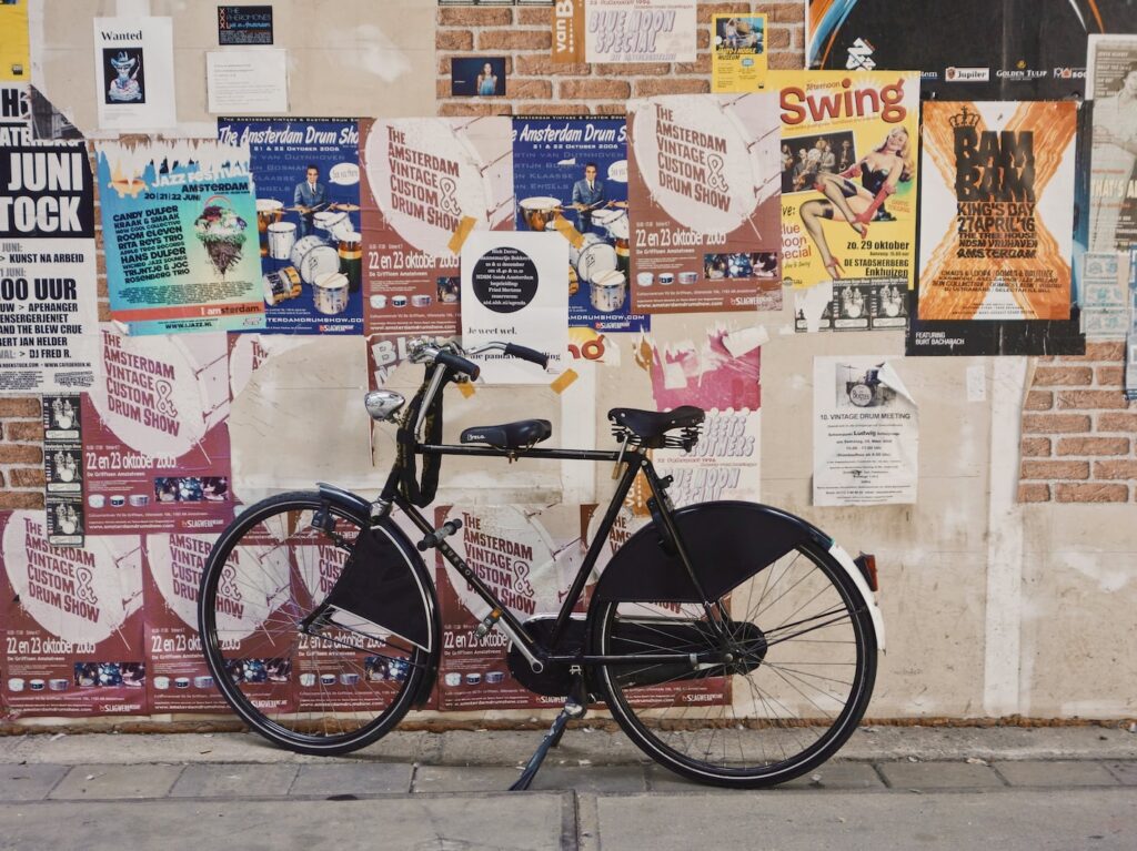 black bicycle parked beside a wall full of poster