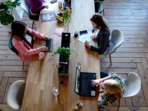 Overhead view of diverse women professionals working in a modern office setting, fostering collaboration and teamwork.