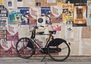 black bicycle parked beside a wall full of poster